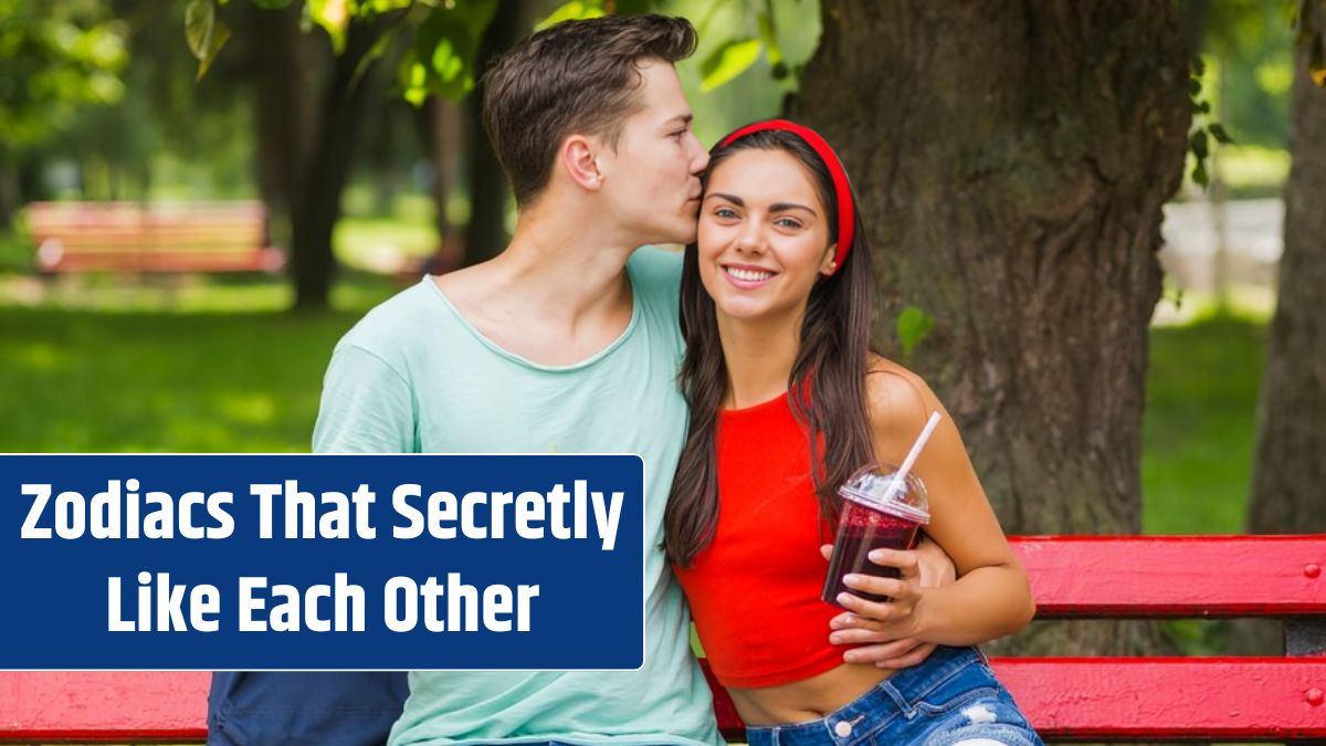 Man kissing her girlfriend holding smoothies in plastic cup.