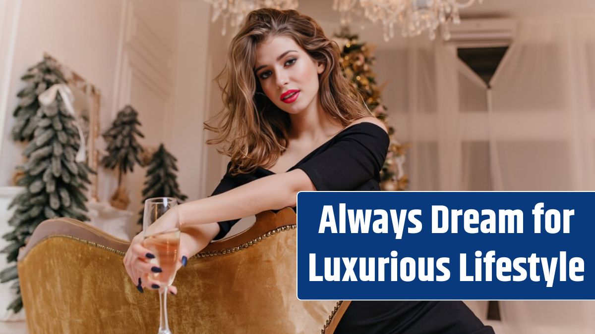 In beautiful designer room with panoramic windows and crystal chandelier, very beautiful woman is sitting on golden sofa, holding glass of sparkling wine.